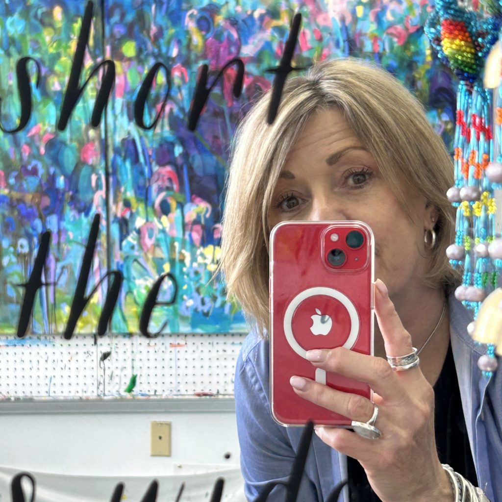 Amanda Onchulenko taking mirror selfie with artwork behind