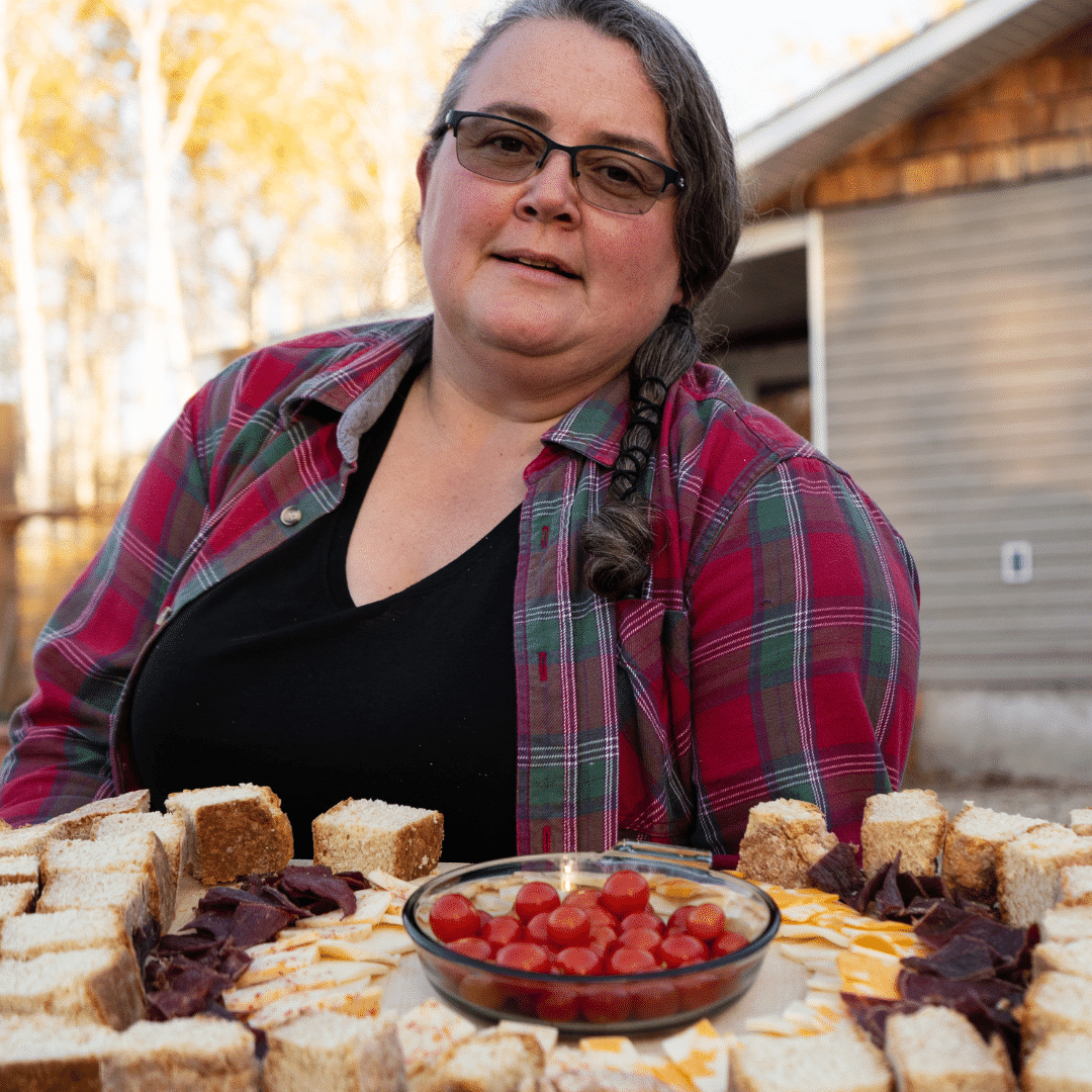Woman in plaid shirt sitting in front of bannock tray