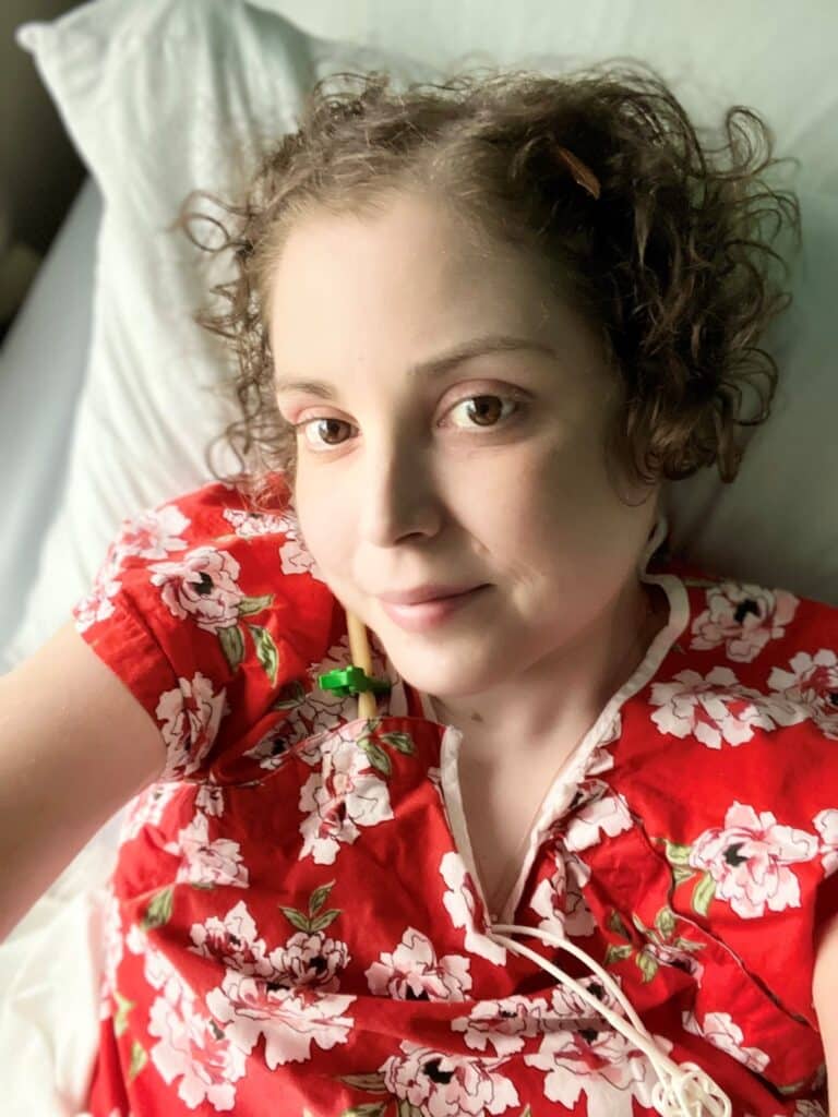 Woman looking up from bed in red floral top