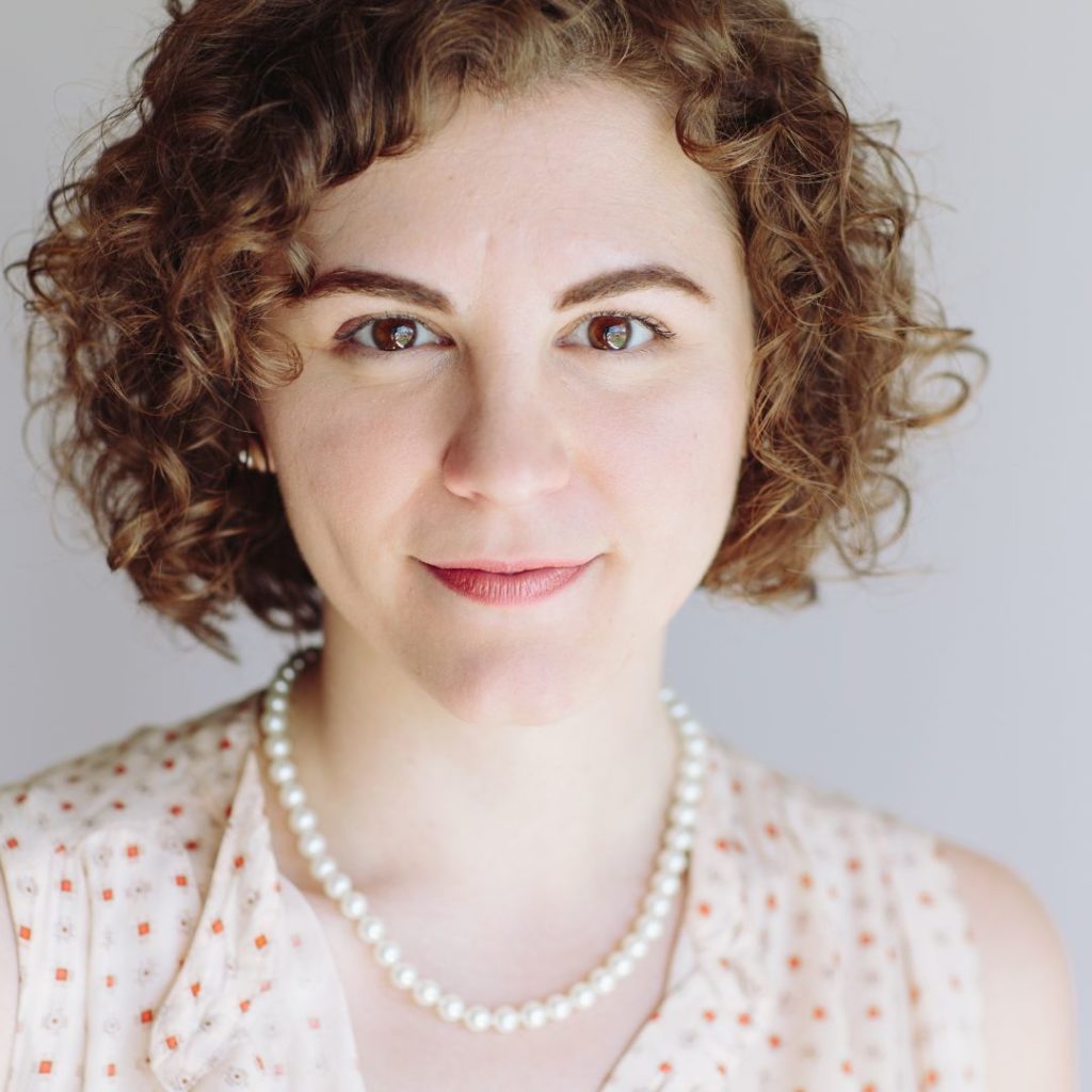 front facing portrait of woman with curly hair wearing pearls