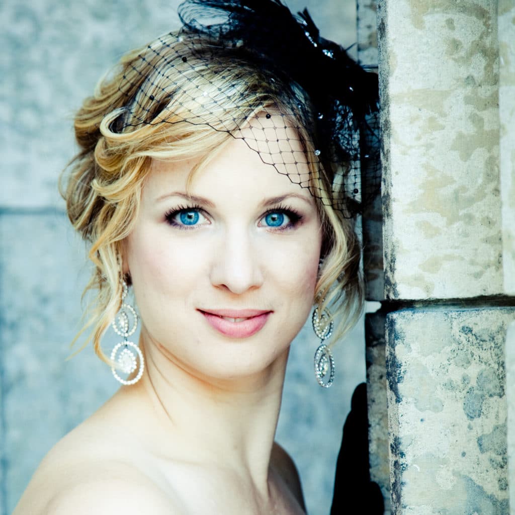 Woman with netted fascinator facing camera